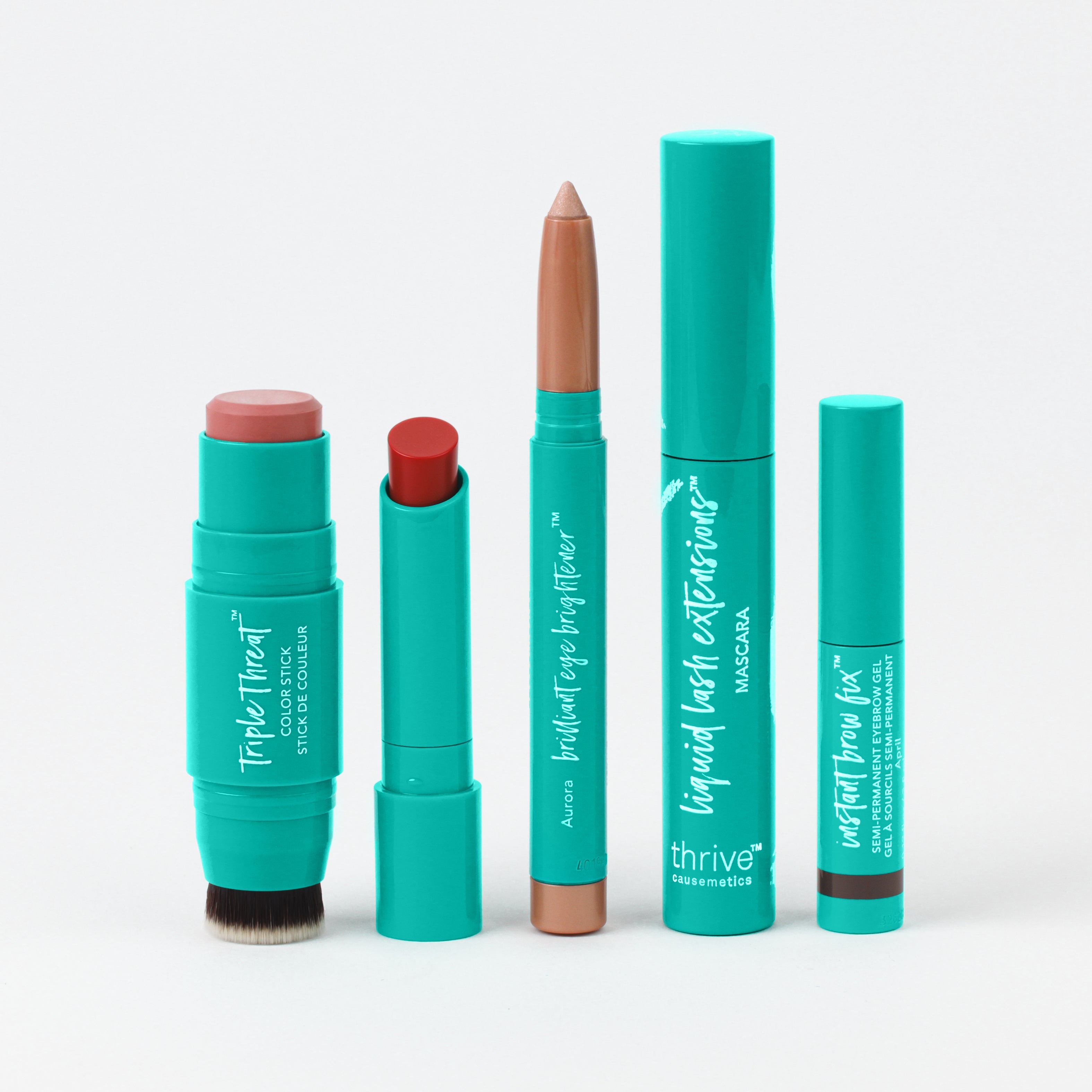 Set of teal makeup products including a blush stick, lip tint, eyeshadow stick, mascara, and brow gel on a white background